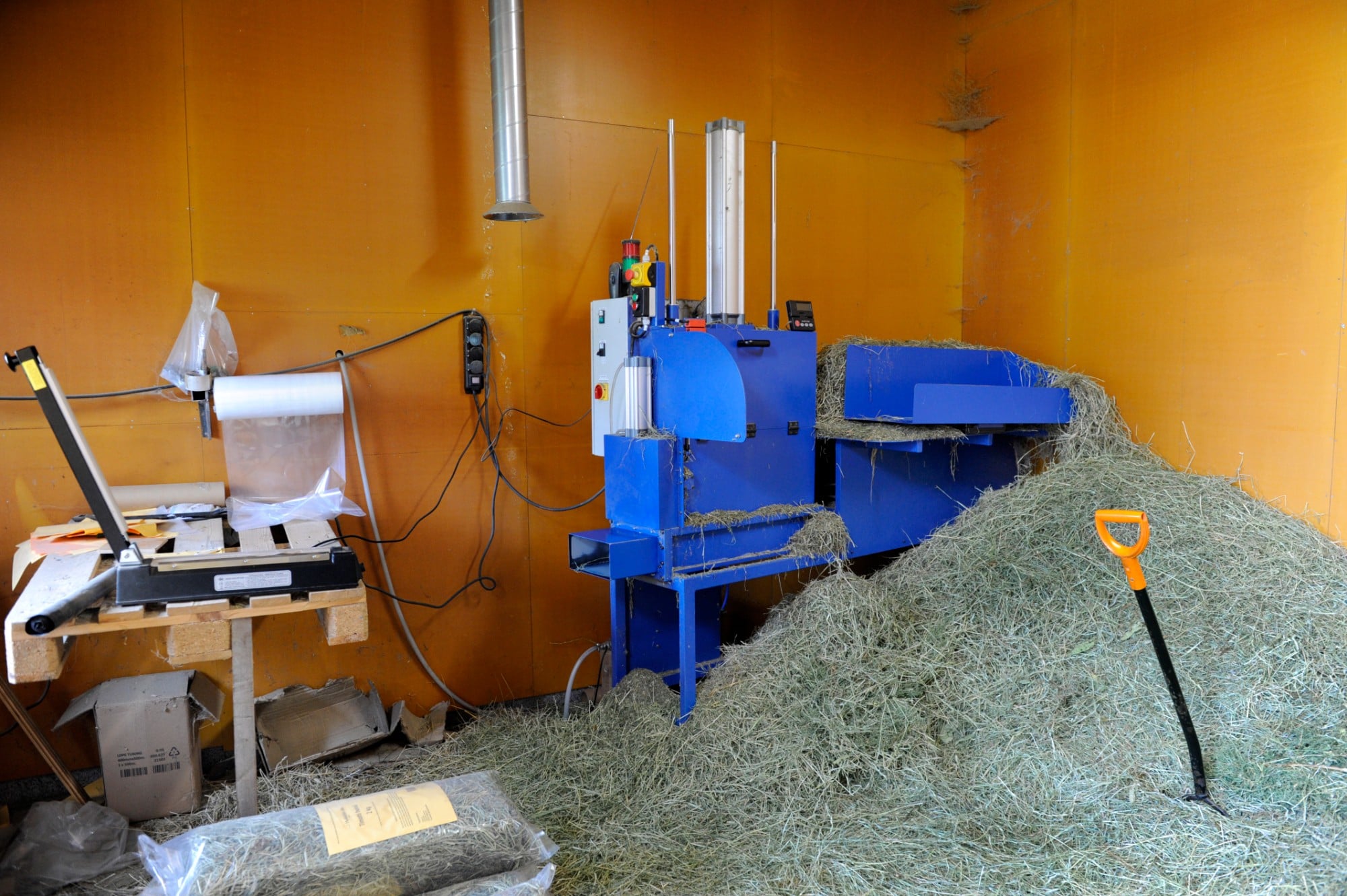 Kaniheinän pakkaamisessa on apuna hydraulinen pakkauskone ja muovisukan saumaaja.